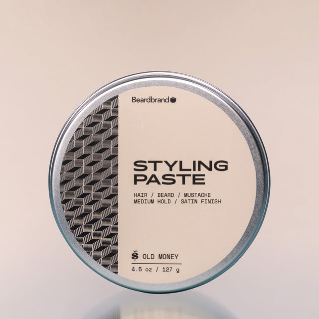 A container of Old Money Styling Paste against a neutral background.
