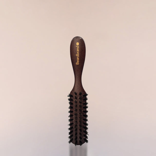 A Beardbrand 100% Boar’s Hair Travel Brush against a neutral background.