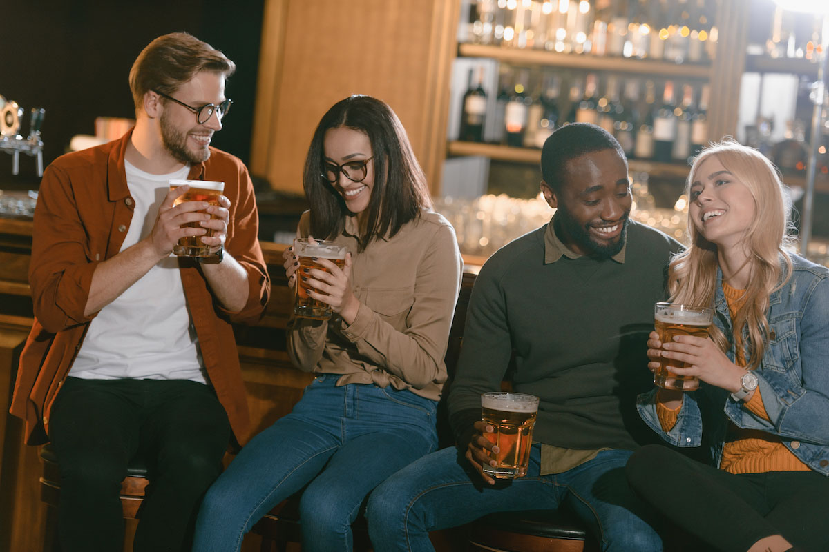 four friends drinking beer at a bar